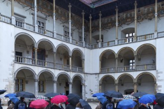 Arcades of the north and east wings of Wavelschloss, in front visitors with umbrellas, Wavelhügel,