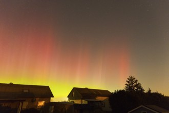 Red and green auroras, stars twinkle over houses and trees, aurora borealis, Ilsede, Lower Saxony,