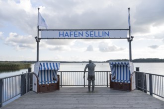 Viewing platform with two beach chairs and a sculpture that looks like a person, sign with flag,