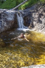 Woman, 45 years old, swimming in Bergbach, Gumpe, natural pool, Upper Bavaria, Alps, Germany