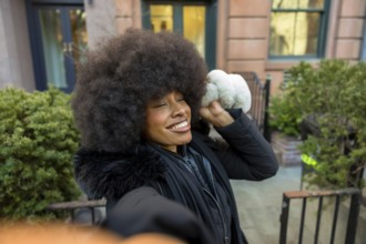Young black woman with a big afro hairstyle taking a selfie, enjoying a sunny winter day in