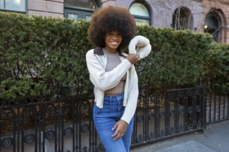 African american woman smiling, showing confident joy and modern fashion, holding a unique fluffy