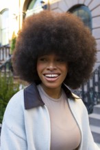African american woman with natural curly afro hairstyle smiling outdoors, representing beauty,