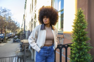 Young woman with an impressive afro hairstyle and casual fashion standing on a residential street