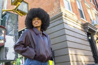 Young african american woman wearing a leather jacket and jeans, standing at a city intersection in