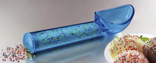 Blue, transparent ice cream scoop filled with coloured sugar sprinkles, next to a plate with