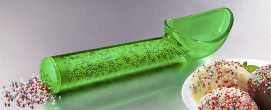 Green, transparent ice cream scoop filled with coloured sugar sprinkles, next to plates with