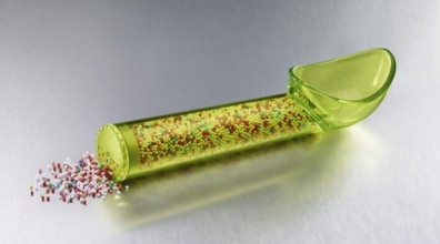 Yellow, transparent ice cream scoop filled with coloured sugar sprinkles