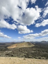 View from Caldera Blanca volcano to Caldereta against blue sky with white clouds, Mancha Blanca,