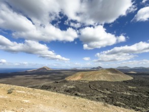 View from Caldera Blanca volcano to Caldereta against blue sky with white clouds, Mancha Blanca,