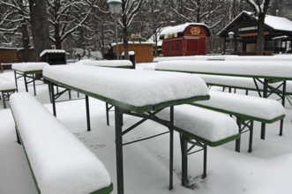 Winter in the English Garden, snow-covered beer garden tables and benches, Munich, Bavaria, Germany