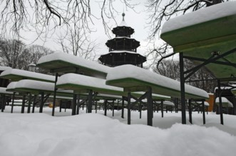 Winter in the English Garden, snow-covered beer garden tables and benches, Chinese Tower, Munich,
