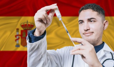 Doctor holding syringe on Spain flag background. Medical professional holding syringe with Spanish