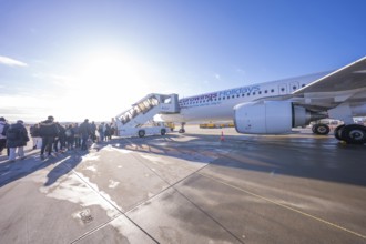 Passengers board an airplane via a mobile staircase under bright blue skies, Stuttgart Airport,