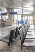 Empty waiting area at the airport with modern rows of seats and light-filled surroundings,