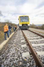 People in orange colors along the train on rails in a rural setting, acceptance of the Hermann