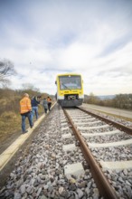 A train on rails with photographers in orange vests in a natural environment, acceptance of the