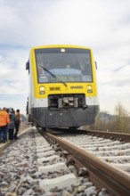 Front view of a train on rails with surrounding people and photographers, acceptance of the Hermann