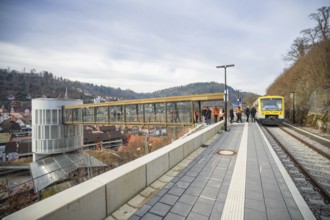 A train approaches a station with a wide panorama and hills in the background, taking off the