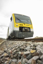 SWEG train on rails with pebbles in the foreground under cloudy sky, taking off the Hermann
