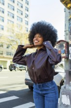 Young african american woman with afro hair smiling confidently on a sunny manhattan street,