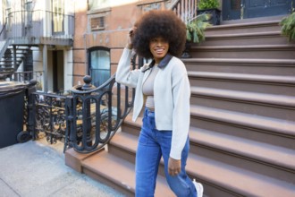 Young black woman embracing urban lifestyle while happily walking down steps of a traditional