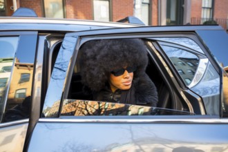 Elegant black woman wearing large sunglasses and an afro hairstyle, looking out of a car window