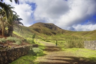 Green hills and walkers under cloudy sky, Yaiza Lanzarote