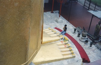 The huge golden Buddha at Wat Indravihan. A Buddhist prays at the feet of the big standing Buddha.