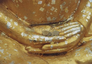 Donations for the temple in the hands of a Buddha sculpture. Buddha, Buddhism, religion, Bangkok,