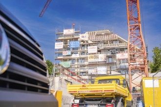 Construction site with crane and yellow construction vehicle in front of a building under