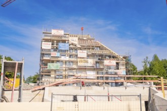 Building under construction with scaffolding and advertising banners under blue sky, carpentry, new