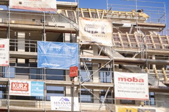 A scaffolding with various corporate advertising banners on a building, carpentry, new building,