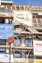 Partially finished building with scaffolding and transparent advertising for craftsmen, carpentry,