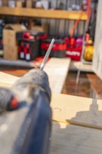 Blurred view of a drill on a construction site with wooden shelves in the background, carpentry,