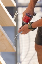 A craftsman drills a screw into a wooden board with precision, carpentry, new building, Stuttgart,