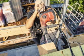 A construction worker uses a drill to work on wood in a construction project, carpentry, new