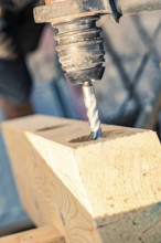 A close-up of a drill drilling a hole in a wooden beam, carpentry, new building, Stuttgart, Germany