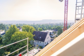 A view from a roof shows a landscape with trees and a crane in the background, carpentry, new