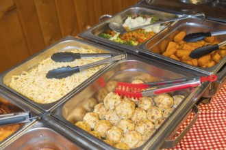 Buffet with various dishes such as cheese spaetzle, dumplings and salad
