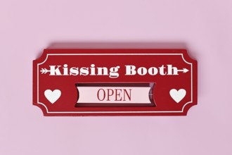Valentine's Day kissing booth sign with hearts on pink background. Romantic love concept flat lay