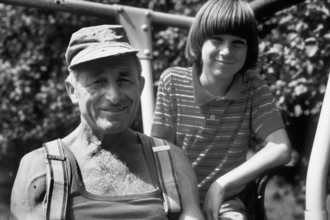 Farmer and his young assistant on the tractor, on a former Franconian farm, black and white,