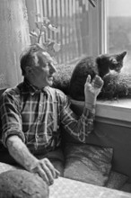 Farmer with a cat at the kitchen window, on a former Franconian farm, black and white, Bavaria,