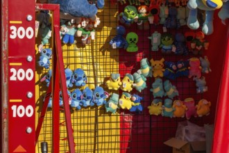 Close-up of blue, yellow and green plush prize dolls at game kiosk at Fun Show traveling ride park,