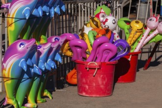 Red plastic buckets with colorful balloons in unusual shapes including cats etc, and dolphins in a
