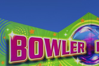 Close-up of the word Bowler painted in purple fluorescent paint on banner at Fun Show traveling