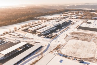 Industrial area in a wintry landscape with factory buildings, forests and snow-covered fields,