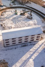 Construction area in snow with construction equipment and a large white building, Nagold, Calw