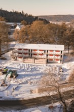 Construction site of a building in snow surrounded by trees and hilly landscape, Nagold, Calw