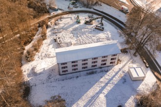 Building on construction site in the forest, surrounded by snow and cranes in a wintry atmosphere,